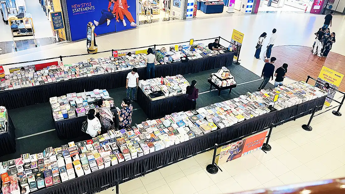Book fest at Surat VR Mall with long tables of books and upto 70 percent off signs, shoppers browsing