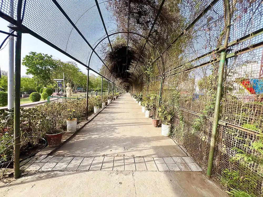 Inside view of Botanical Garden Surat showing a long arched net walkway with potted plants on both sides