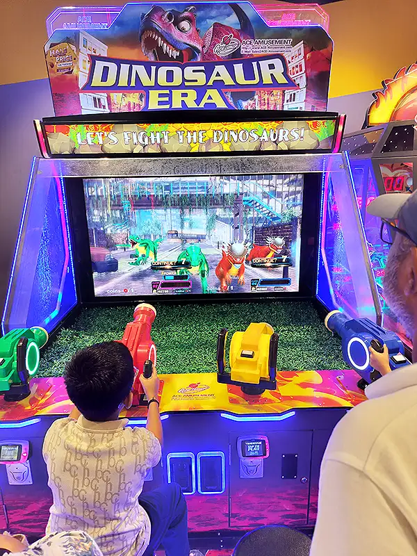 Kids playing Dinosaur Era shooting arcade game at Surat VR Mall game zone with colorful toy guns