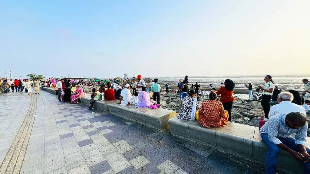 Families sitting along the seating wall at Dumas Sea Face Surat