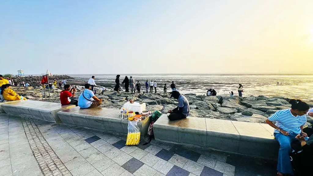 Food vendor selling snacks near seating wall at Dumas Sea Face Surat