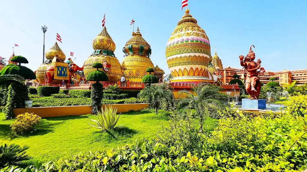Green garden with golden kalash domes and statue at Swaminarayan Gurukul Surat