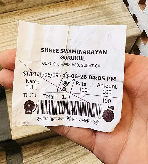 Hand holding Shree Swaminarayan Gurukul ticket priced at ₹100
