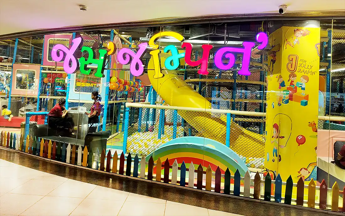 Colorful Jus Jumpin kids play area at Surat VR Mall with yellow tube slide, ball pit and soft play behind glass