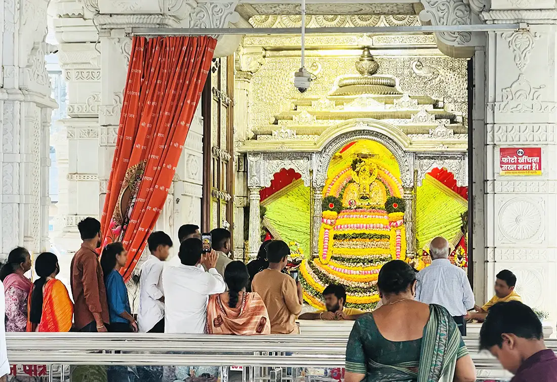Devotees taking darshan of Shyam Baba at the Surat temple, deity decorated with yellow and pink flower garlands