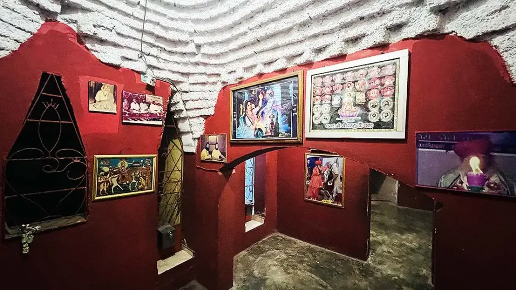 Cave interior at Mini Girnar Ram Madhi Surat with multiple framed photos of saints and mahatmas