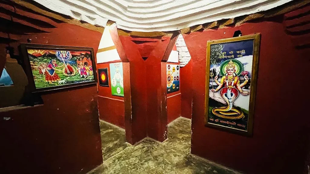Inside cave of Ram Madhi Surat with framed paintings of Hindu saints and deities on red walls