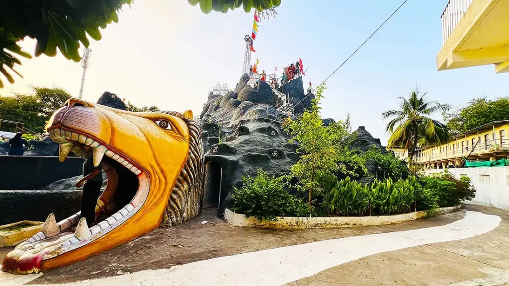 Animal face exit gate at Ram Madhi Surat Mini Girnar with open mouth and rocky structure behind