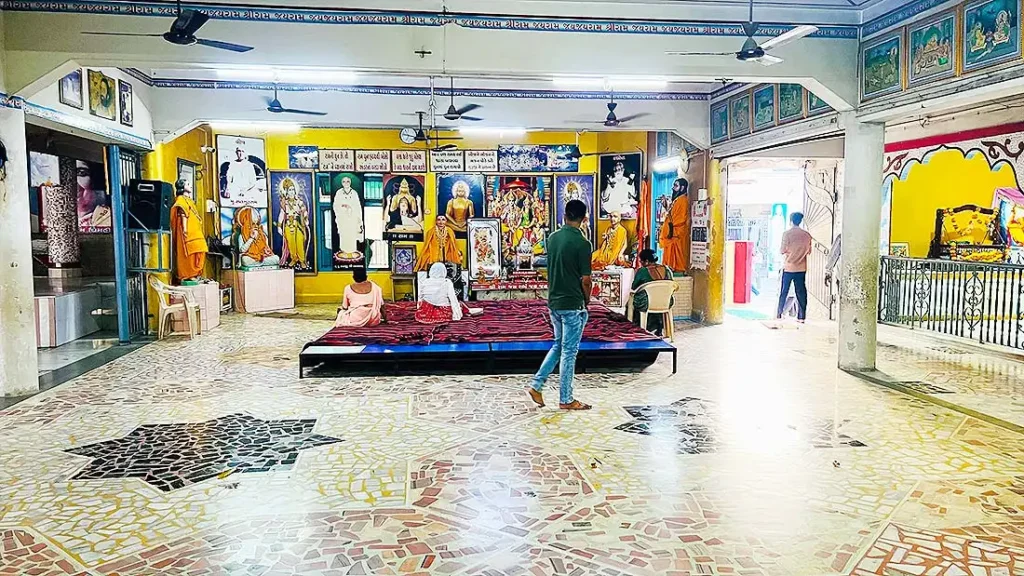 Inside Ramdev Pir mandir at Ram Madhi Surat with deity statues, devotees and kirtan stage