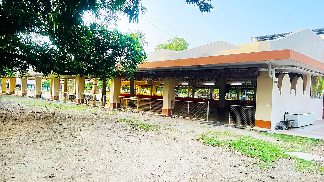 Back view of the open satsang hall at the Jahangirpura ashram, showing pillared sides and a large clearing in front