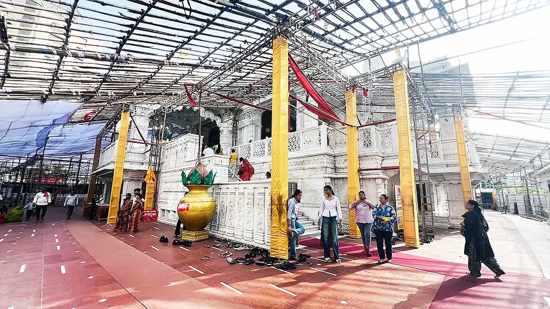 Side view of the white marble Shyam temple on VIP Road, with yellow wrapped pillars and a canopy frame overhead