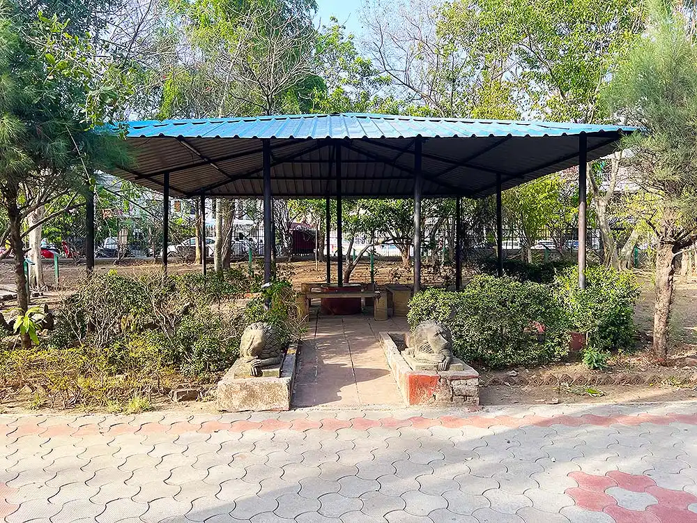 Covered sitting area and relaxation zone at Botanical Garden Surat with benches and green surroundings