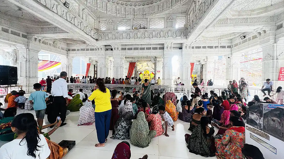 Devotees seated inside the white marble hall of Khatu Shyam temple Surat on a busy Sunday for darshan