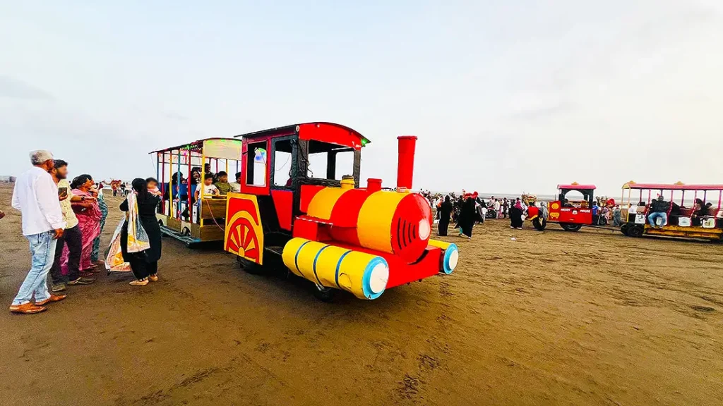 Red and yellow toy train ride at Dumas Beach Surat