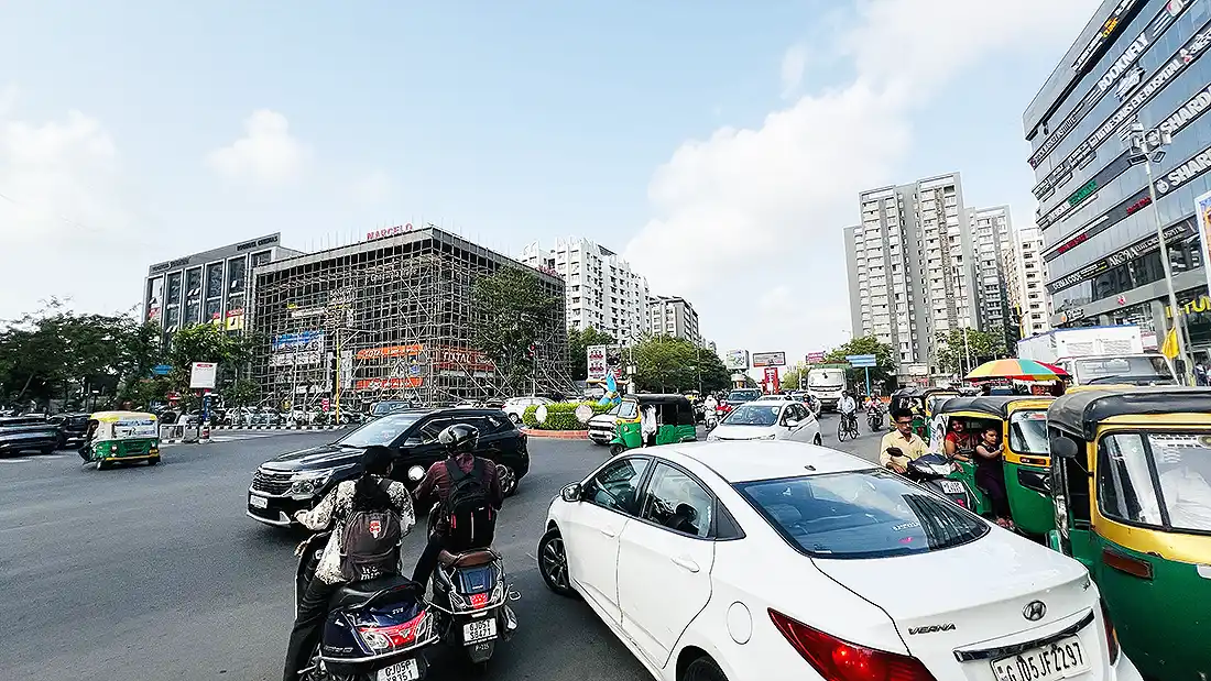 Heavy traffic at the circle outside Khatu Shyam temple on VIP Road, Vesu, with cars, bikes and auto rickshaws jammed together