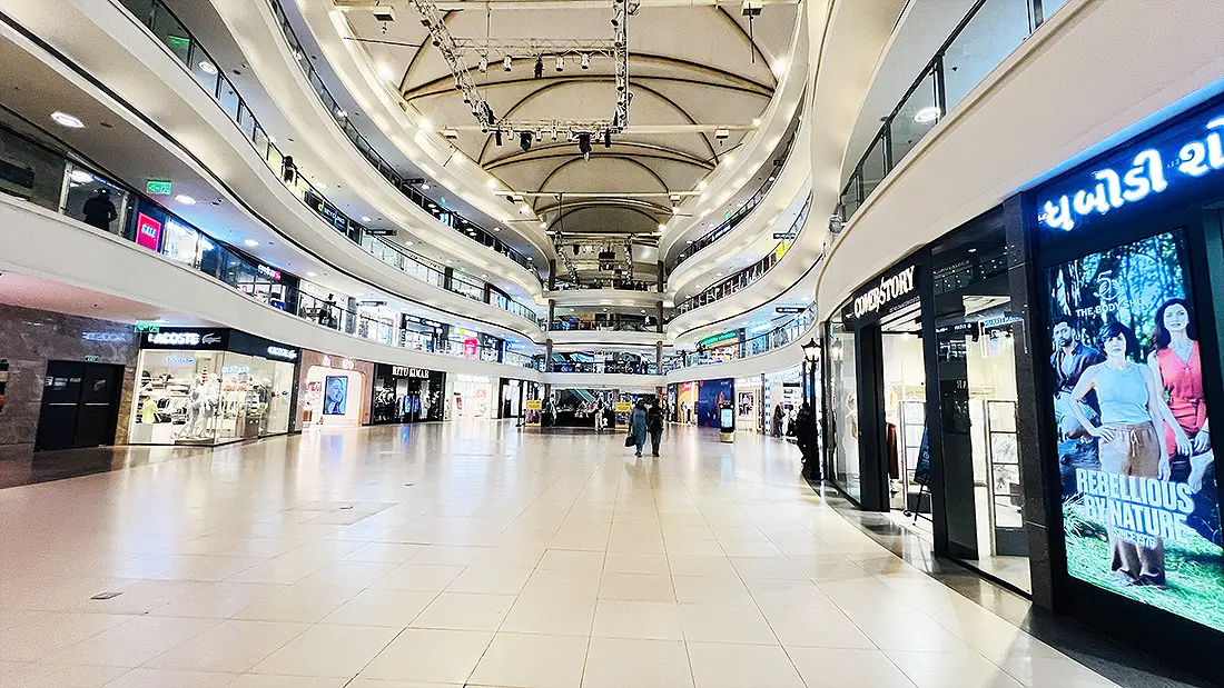 Spacious inside view of VR Mall Surat with multiple curved floors, storefronts and a wide tiled walkway