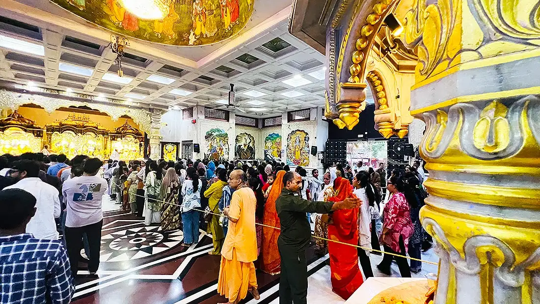 Female devotees in the separate women section at ISKCON Temple with a golden carved pillar in front